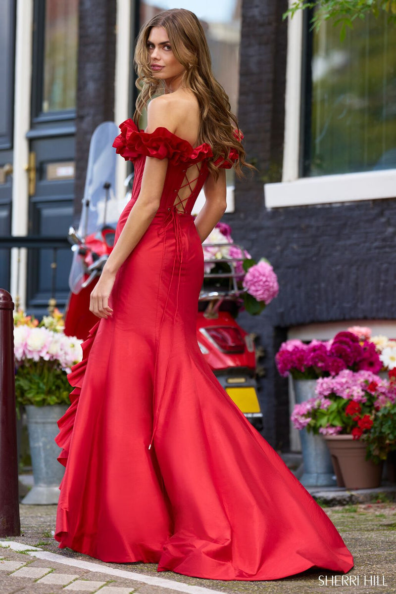 This dress features an off-the-shoulder neckline with a ruffle detail, a lace-up back and a corset bodice with boning, a fitted silhouette and ruffle detailing following the slit hemline. This dress is playful and unique and could be just the vibe for your next prom or formal event.  Sherri Hill 56240