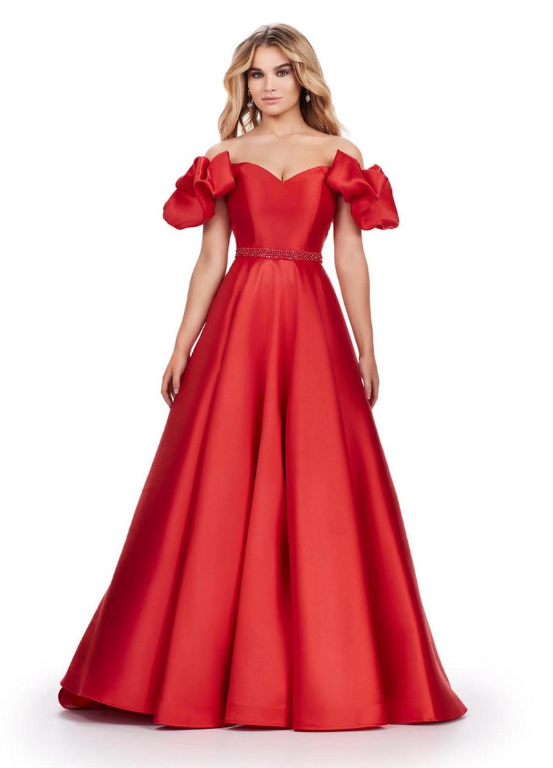 This gown features an off the shoulder neckline with puff sleeve details and a sweetheart neckline. This dress also has a beaded waistline, an A-line silhouette with a slight train and mikado fabric. This is a playful and feminine choice for your next prom or formal event.  Ashley Lauren 11542