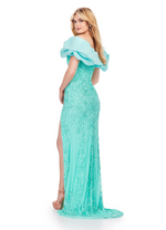 This statement dress features a off-the-shoulder neckline and fully beaded fabric with an intricate design. The oversized taffeta ruffle adds volume and a unique detail. This dress has a side slit with a slight train. This gown is unique and unforgettable, and it could be perfect for your next prom, pageant, or formal event.   Ashley Lauren 11581