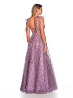 This dress features a sheer illusion corset bodice with tie straps, and illusion lace-up back, a full sweeping skirt with a side slit and asymmetrical ruffle detail all on a printed tulle. This dress is playful and feminine and ideal for your prom or formal event.   DJ 11591