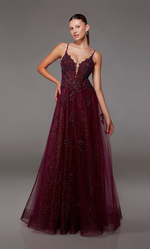 This gown features a deep v-neckline with spaghetti straps and a lace-up back. The bodice is adorned with lace appliqué and the skirt features a glitter tulle fabric and an A-line silhouette. This dress is romantic and unique and could be just the vibe for your next prom or formal event.   Alyce 1824