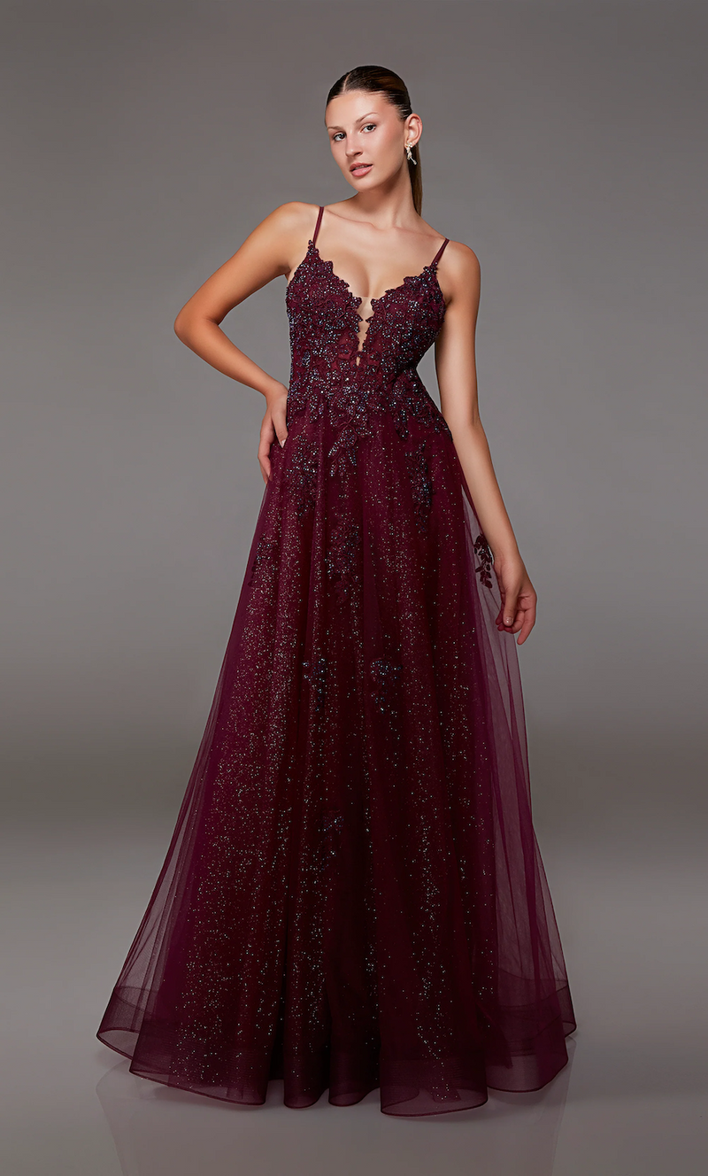 This gown features a deep v-neckline with spaghetti straps and a lace-up back. The bodice is adorned with lace appliqué and the skirt features a glitter tulle fabric and an A-line silhouette. This dress is romantic and unique and could be just the vibe for your next prom or formal event.   Alyce 1824
