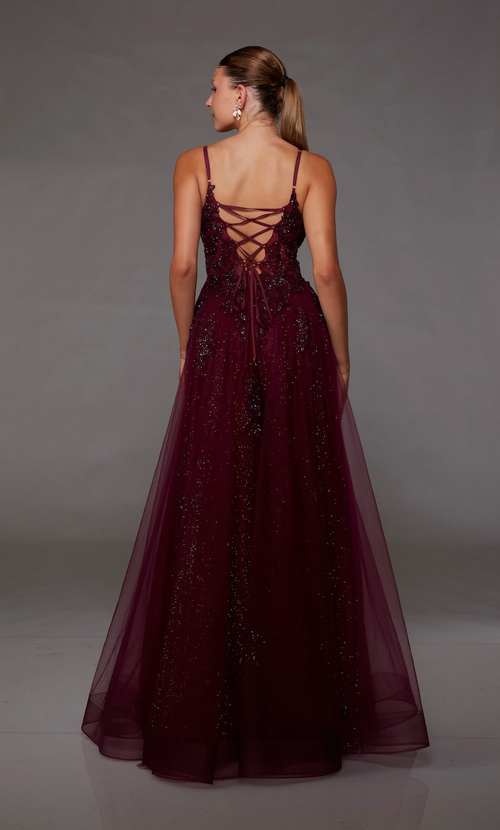 This gown features a deep v-neckline with spaghetti straps and a lace-up back. The bodice is adorned with lace appliqué and the skirt features a glitter tulle fabric and an A-line silhouette. This dress is romantic and unique and could be just the vibe for your next prom or formal event.   Alyce 1824