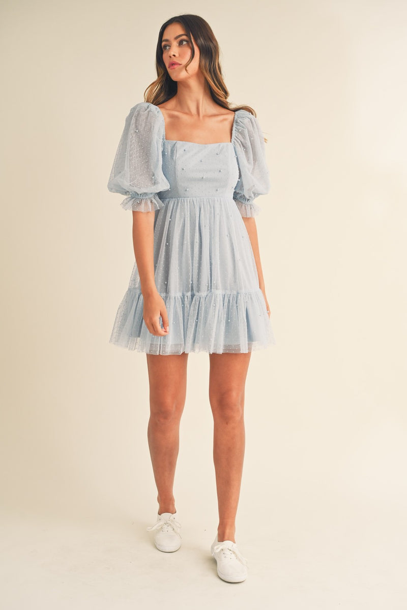 This dress features pearl stud swiss dot mesh with a short puff ruffle sleeve a babydoll silhouette with an open-back self-tie detail. This playful dress is an excellent choice for your next homecoming, sweethearts dance or formal event!  MAE-MD4369