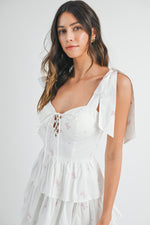 This cocktail dress features bow embroidery throughout the fabric, a sweetheart neckline with a tie in the front of the bodice and shoulder bow tie details as well. The skirt has tiered ruffle layers creating an A-line silhouette. Style this dress to make it your own at your next homecoming, sweethearts or formal event.&nbsp;    MAE MD3130B
