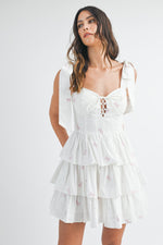 This cocktail dress features bow embroidery throughout the fabric, a sweetheart neckline with a tie in the front of the bodice and shoulder bow tie details as well. The skirt has tiered ruffle layers creating an A-line silhouette. Style this dress to make it your own at your next homecoming, sweethearts or formal event.&nbsp;    MAE MD3130B