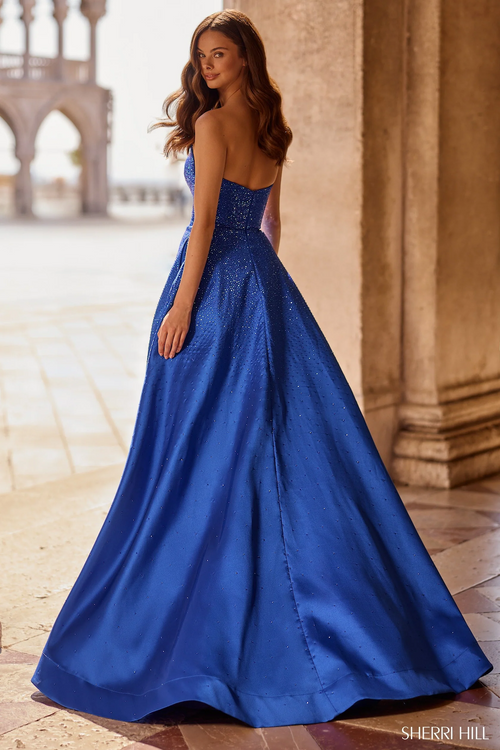 This gown features a strapless neckline with hot fix stones throughout the fabric, a skirt slit, and an A-line silhouette with illusion side cutouts. Style this dress to make it your own at your next prom or formal event.

Sherri Hill 57402