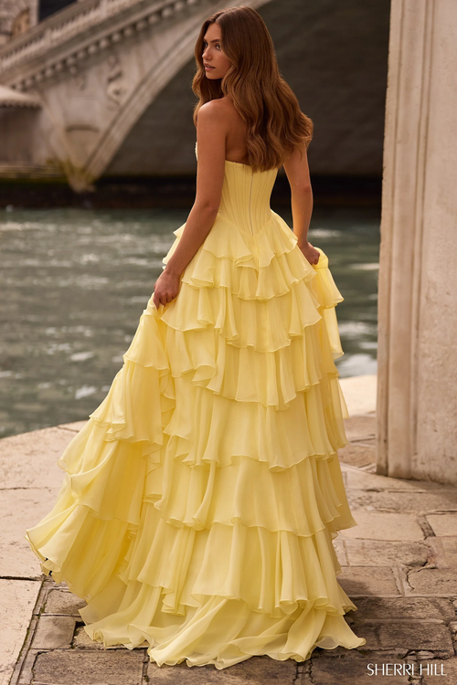 This strapless ballgown features a corset bodice with lace applique on the bust and a chiffon ruffle skirt with a slit. Make a statement at your next prom or formal event in this gorgeous gown.&nbsp;

Sherri Hill 57541