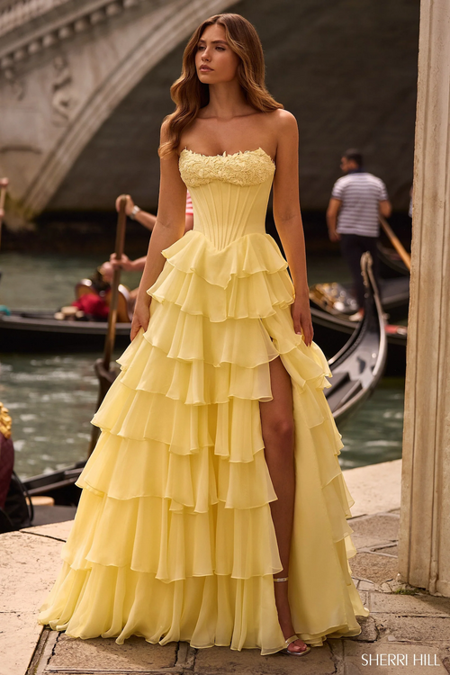 This strapless ballgown features a corset bodice with lace applique on the bust and a chiffon ruffle skirt with a slit. Make a statement at your next prom or formal event in this gorgeous gown.&nbsp;

Sherri Hill 57541
