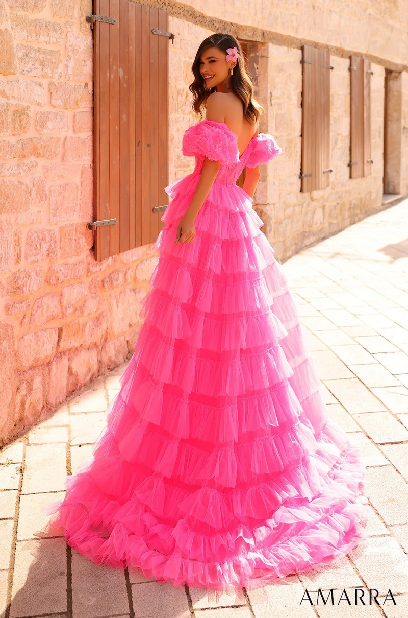 This dress is designed with accentuated ruffled details around the burst and the sheer corset bodice. The tiered tulle gown with ruffle embellishment and the off-shoulder puffed sleeves create a fun and playful vibe. With a mid-open scoop back, tulle fabric and a sweep train, this dress has all the flair to make an entrance at your next prom or formal event.  AUA 94000