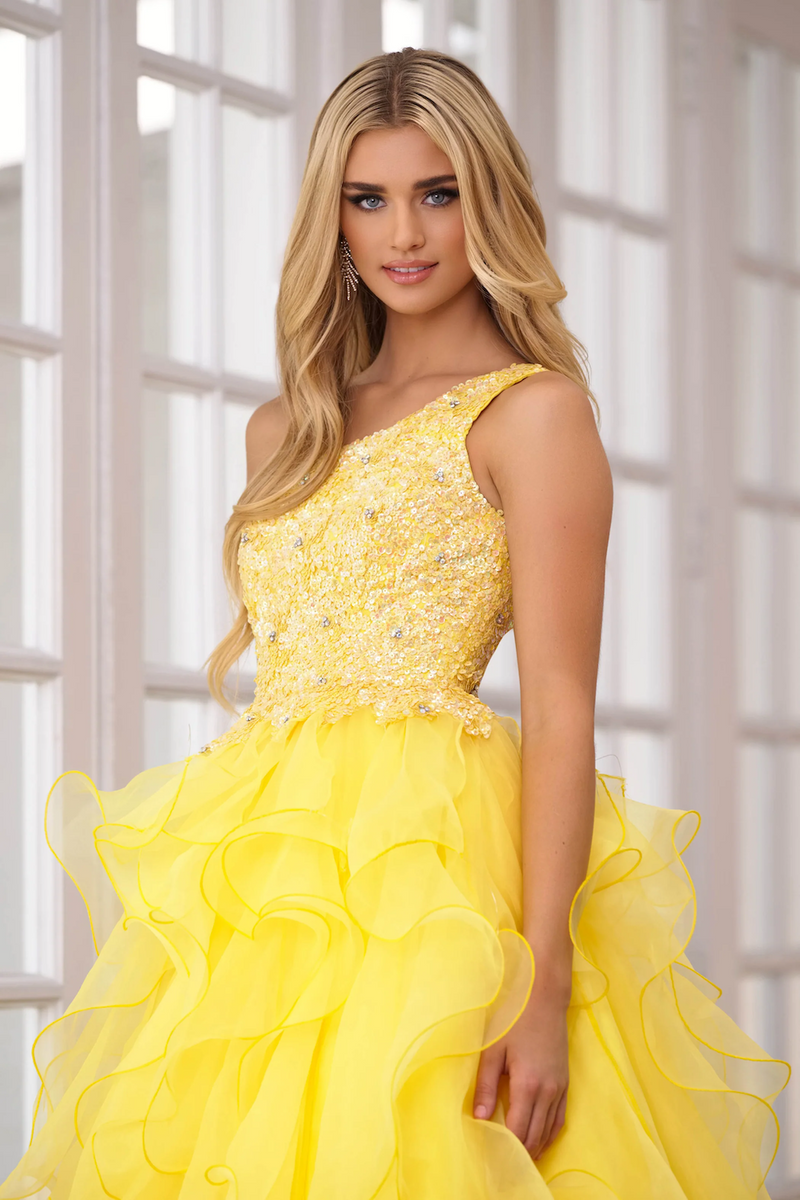 This gown features a one-shoulder neckline with a bodice embellished with sequins and crystal beading. The skirt has layered ruffle fabric which adds volume and playfulness. This gown may be ideal for your next prom or formal event.  ARY 28576