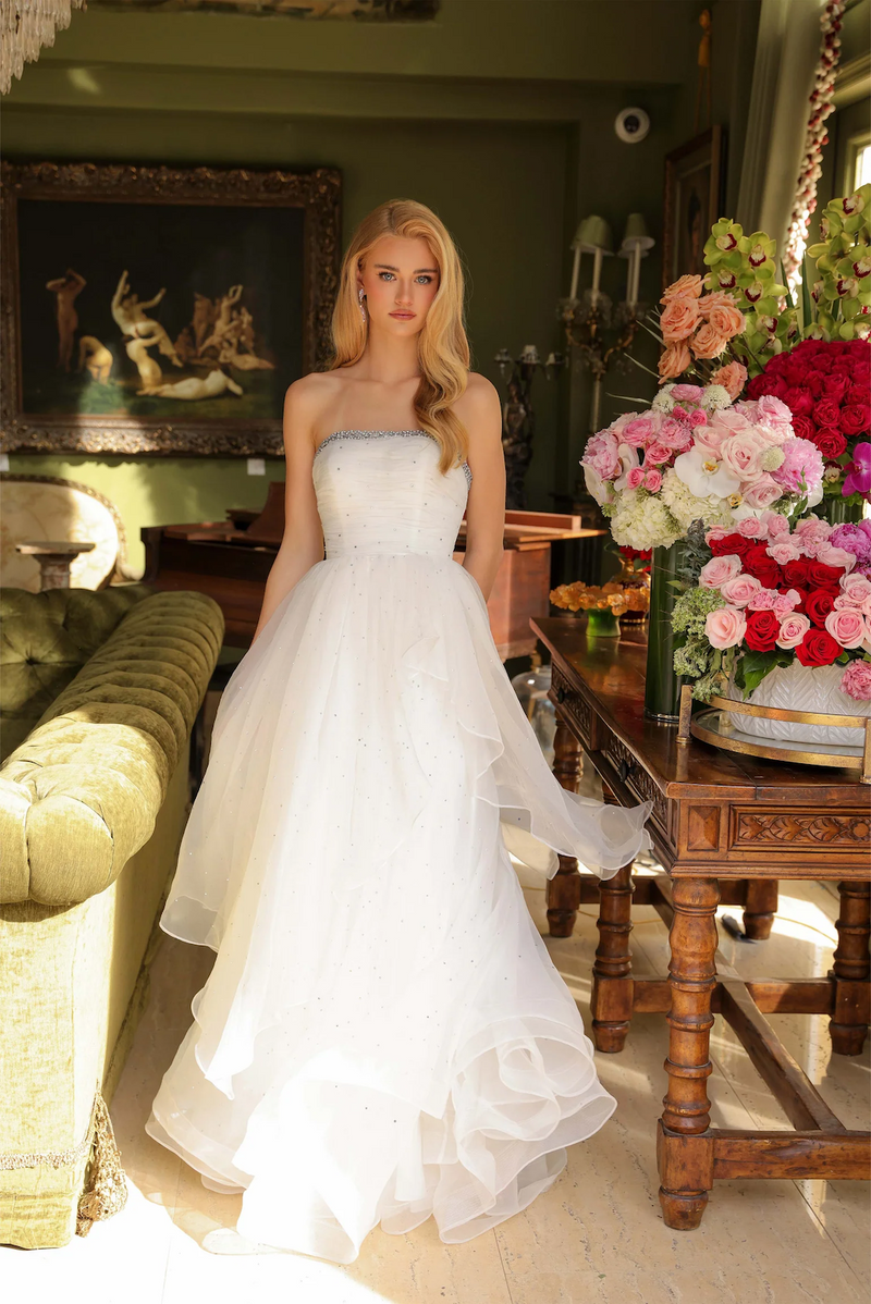 This strapless dress features a subtly crystal embellished bodice that gently flows into a layered, full skirt, perfect for creating a soft and romantic silhouette. Whether for a prom, or any formal occasion, this gown exudes grace and sophistication all night long.

ARY 29524