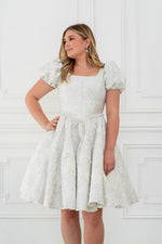 This dress features a shimmering brocade fabric that catches the light with every movement. The hidden structured boning and soft square neck provides a flattering, corset-like fit, while the full zipper back ensures effortless wear. The puff sleeves add a touch of romance, making it perfect for your next homecoming or formal event.

AG 11003