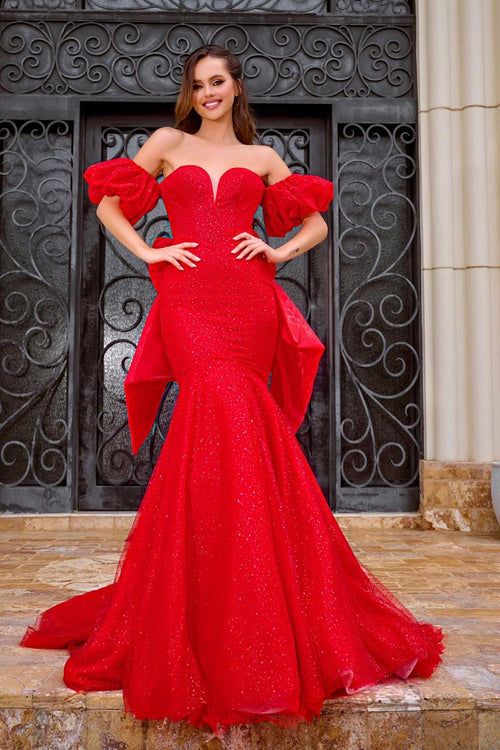 This dress features a sweetheart neckline with a slight plunge, off-the-shoulder puff sleeves, a mermaid silhouette with glitter fabric. This gown has a lace-up back and a dramatic bow with crystal bead details. A feminine and stunning choice for your next prom or formal event.  AE PS24065