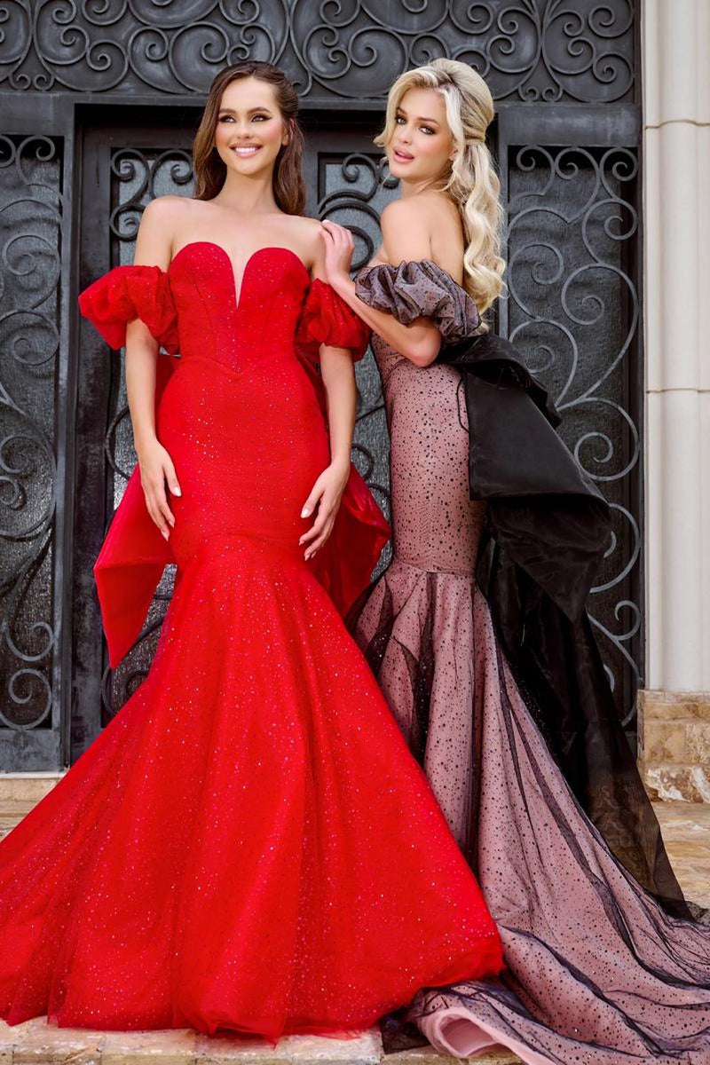 This dress features a sweetheart neckline with a slight plunge, off-the-shoulder puff sleeves, a mermaid silhouette with glitter fabric. This gown has a lace-up back and a dramatic bow with crystal bead details. A feminine and stunning choice for your next prom or formal event.  AE PS24065