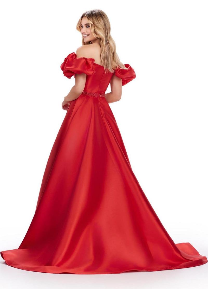 This gown features an off the shoulder neckline with puff sleeve details and a sweetheart neckline. This dress also has a beaded waistline, an A-line silhouette with a slight train and mikado fabric. This is a playful and feminine choice for your next prom or formal event.  Ashley Lauren 11542