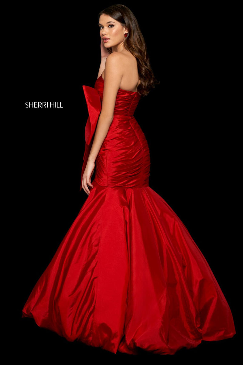 This Sherri Hill dress features taffeta fabric with a mermaid silhouette, a strapless neckline, pleated bodice and large embellished bow on the hip. This one-of-a-kind dress may be the perfect fit for your next prom or formal event.   Sherri Hill 54027