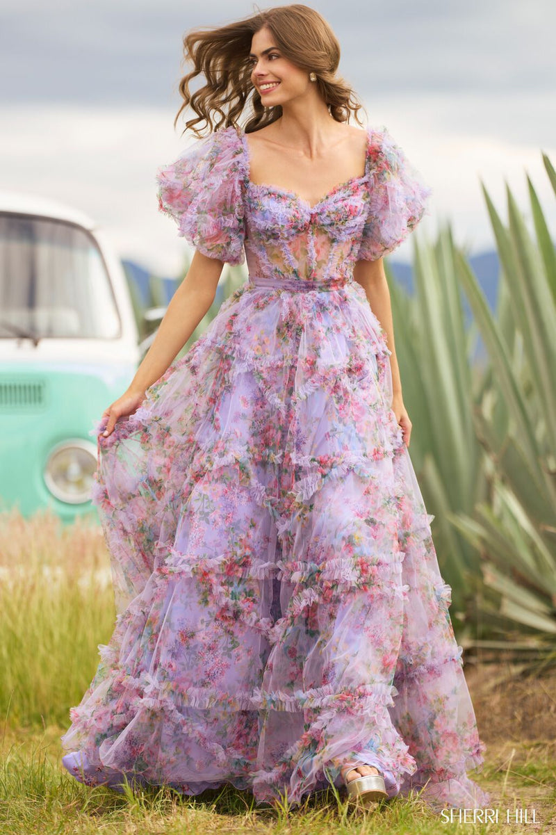 <p><span>This gown features tulle floral print fabric with a sheer corset bodice with ruffle embellishments and balloon sleeves. The neckline is off-the-shoulder, with a belt tie along the waistline and the skirt has ruffle detailing throughout. This dress has a romantic, boho-vibe which may be perfect for your next prom or formal event.</span></p> <p>Sherri Hill 55541</p>