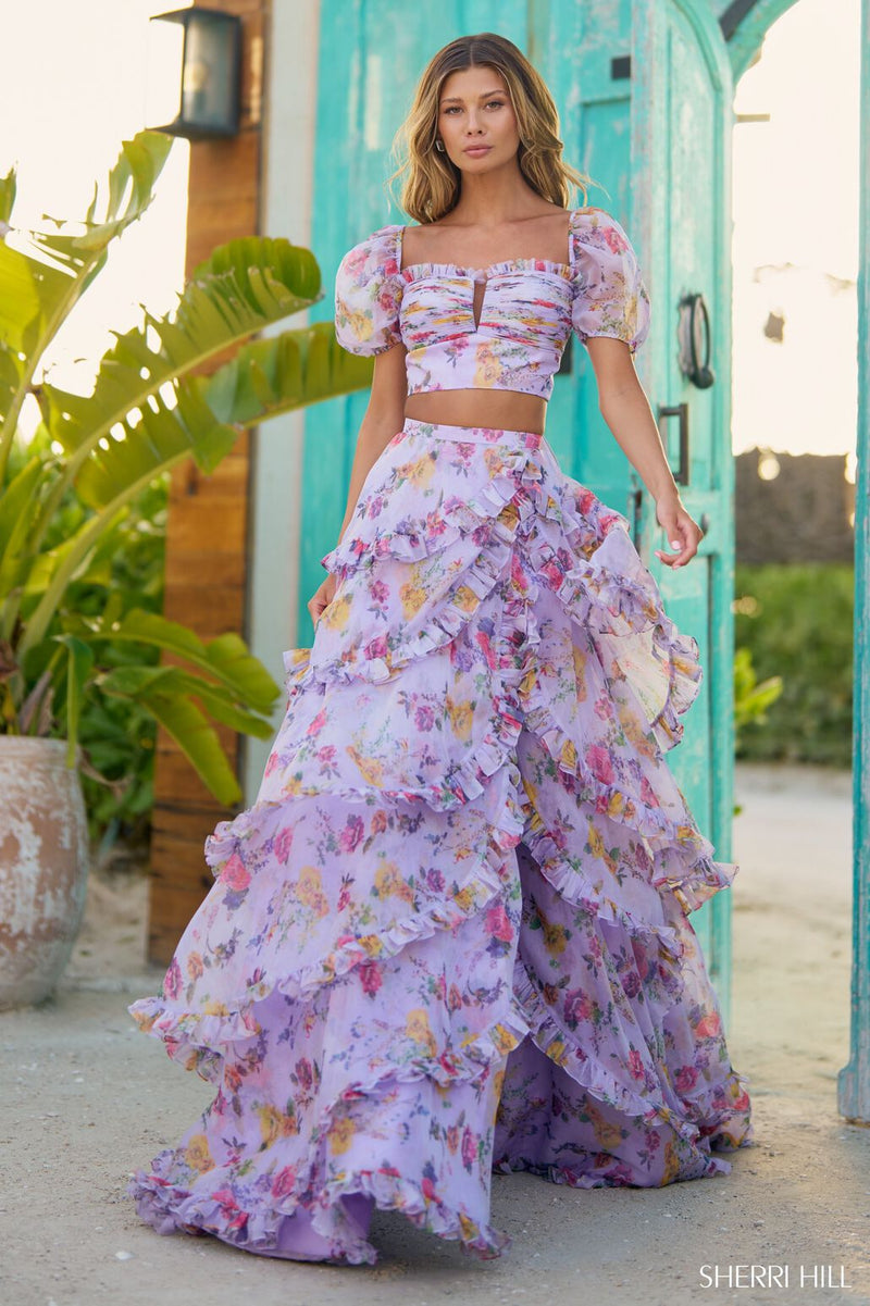 This gown features a two-piece A-line silhouette with floral print chiffon fabric, balloon sleeves and a tiered ruffle skirt and slit. This dress is unique and feminine and a sure stand-out at your next prom or formal event.  Sherri Hill 56024