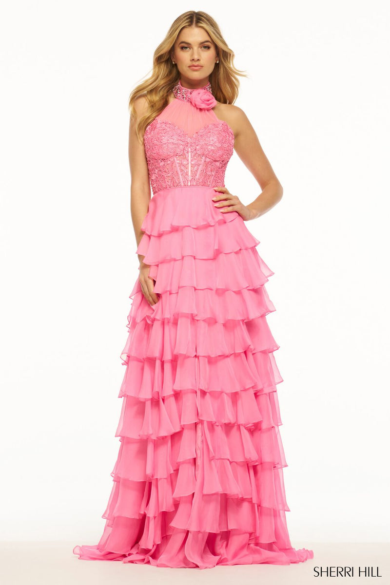 This Sherri Hill gown features a leaf lace high neckline with a beaded choker and 3D flower. It has a layered ruffle chiffon skirt and slit. This dress is playful and unique and could be perfect for your next prom or formal event! Sherri Hill 56083