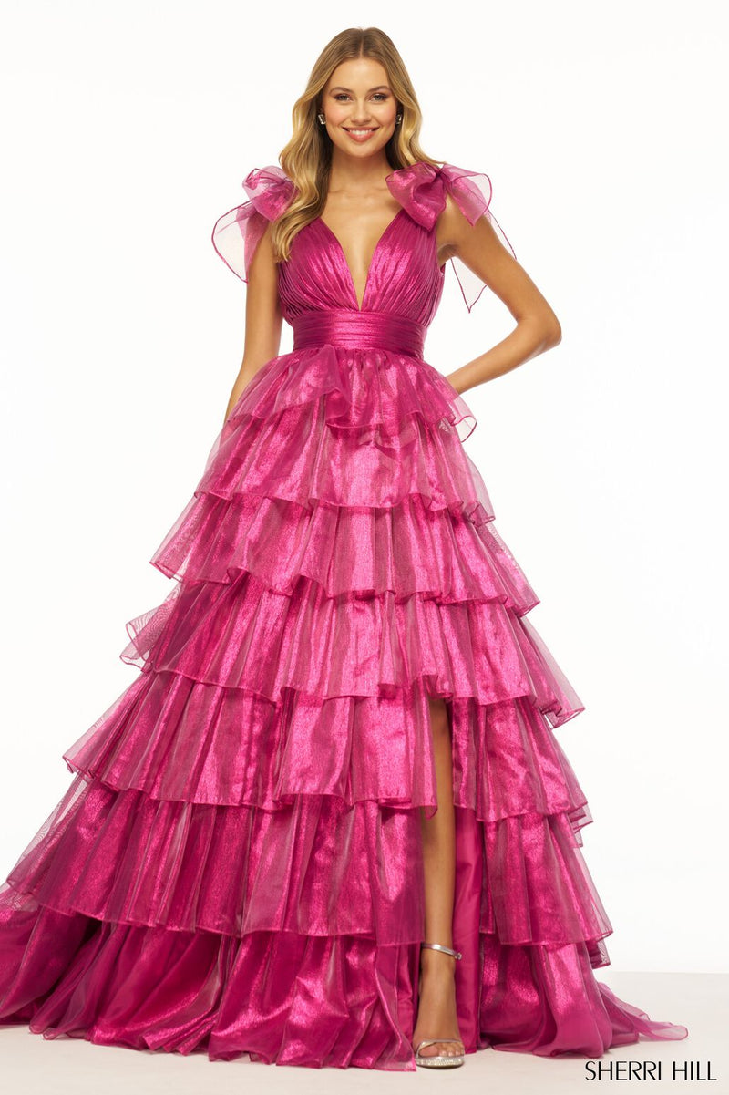 This Sherri Hill ballgown features sparkle organza fabric with a ruffle skirt, bow-embellished straps, a deep v-pleated neckline, and a skirt slit. This dress is vibrant and could be ideal for your next prom or formal event!  Sherri Hill 56127