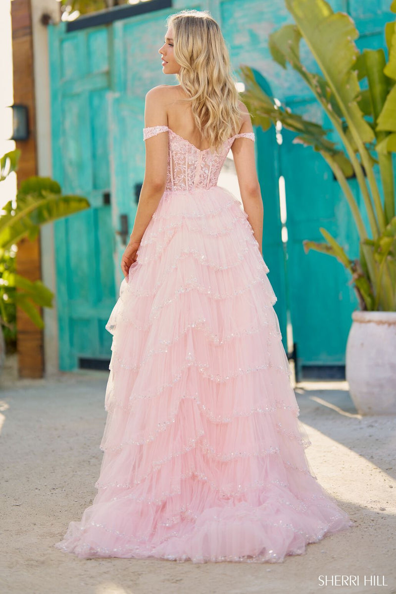 This Sherri Hill gown features a tulle sequin fabric, an A-Line silhouette with a sheer corset bodice, off-the-shoulder straps and a ruffle high-slit skirt. All the details in this dress culminate to create a stunning effect. It's giving the ultimate prom experience.   Sherri Hill 56157