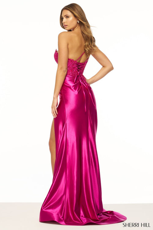 This Sherri Hill gown features a one-shoulder neckline with a lace bodice, flower embellishments, a sheer deep V neckline, and a ruched stretched satin skirt with slit. Could this dress be the one for your next prom or formal event?  Sherri Hill 56174