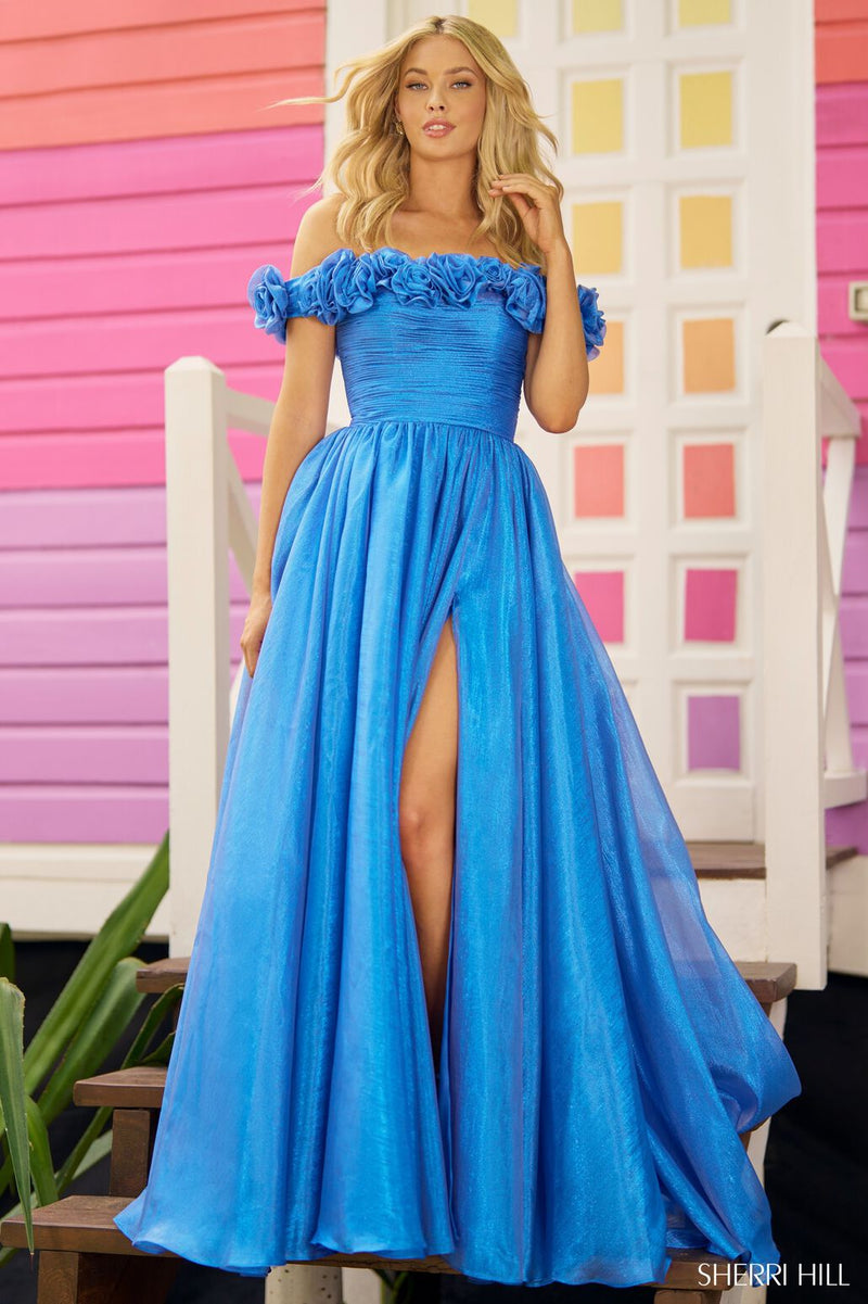 This Sherri Hill gown features sparkle tulle fabric with an off-the-shoulder neckline, an A-line silhouette with rosette embellished top and a skirt slit. This dress is perfect for your next prom or formal event!  Sherri Hill 56194
