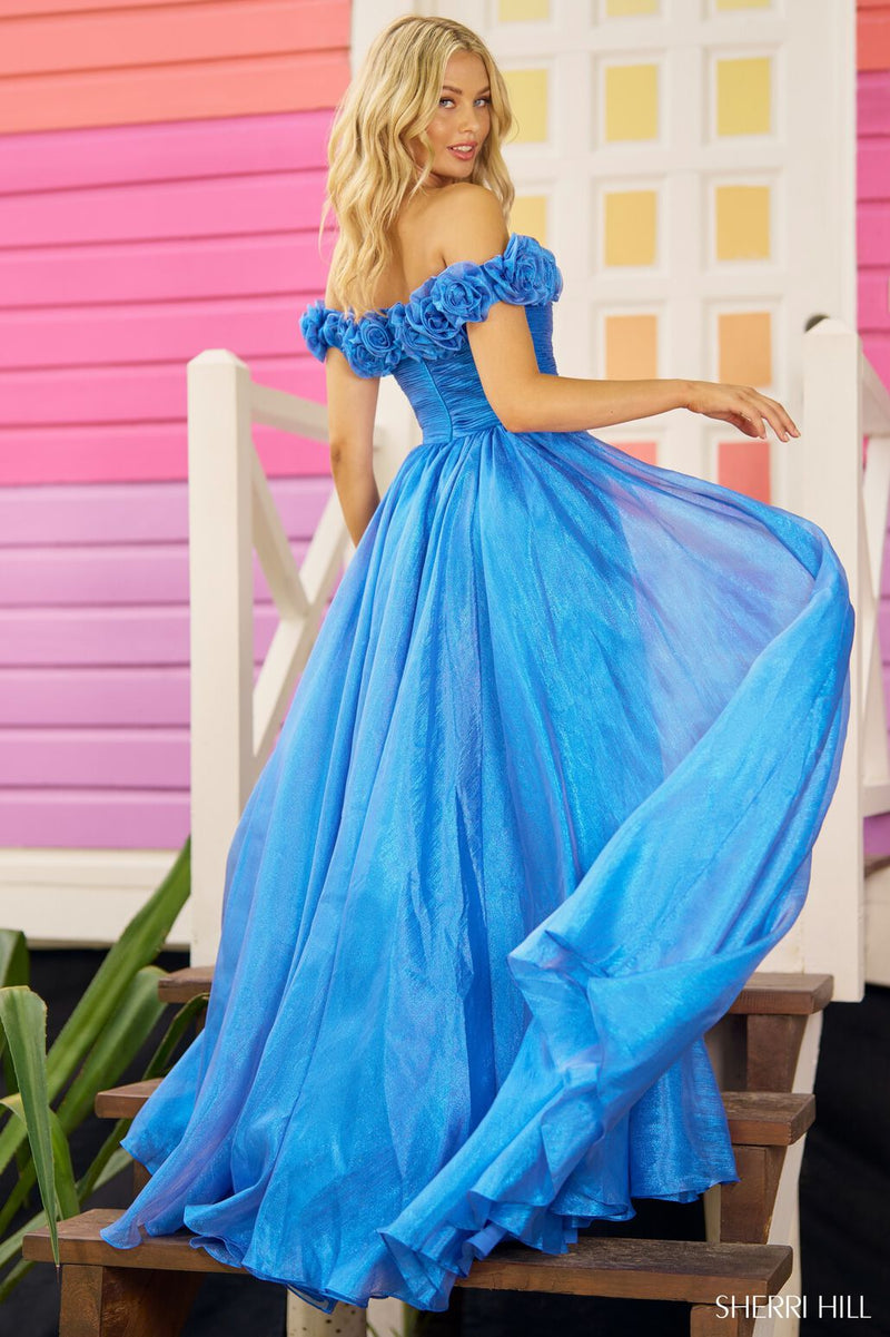 This Sherri Hill gown features sparkle tulle fabric with an off-the-shoulder neckline, an A-line silhouette with rosette embellished top and a skirt slit. This dress is perfect for your next prom or formal event!  Sherri Hill 56194