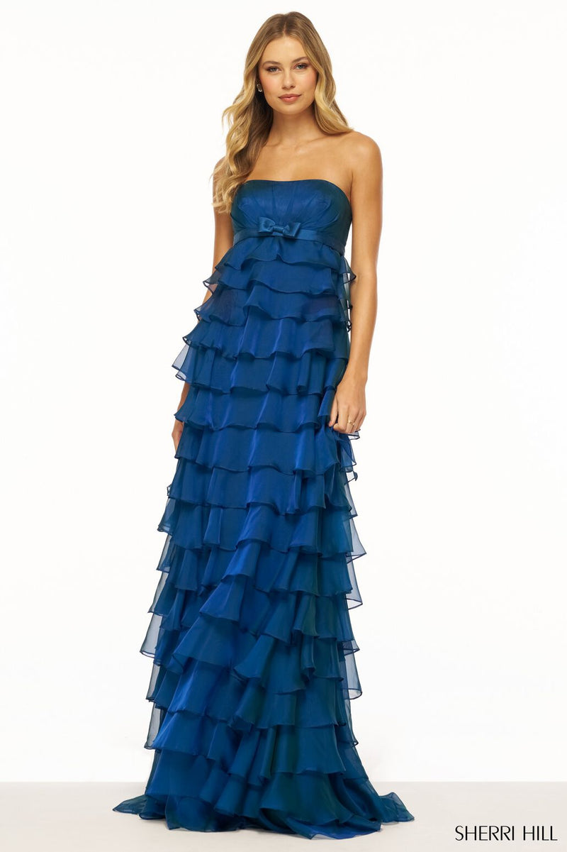 This dress features a strapless neckline with a ruffle tiered skirt and bow embellishment along the empire waist belt. This dress is unique and feminine and could be ideal for your next prom or formal event.  Sherri Hill 56226