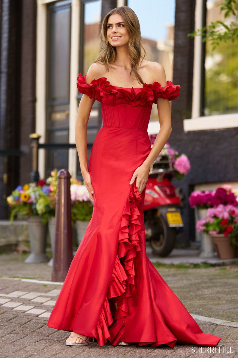 This dress features an off-the-shoulder neckline with a ruffle detail, a lace-up back and a corset bodice with boning, a fitted silhouette and ruffle detailing following the slit hemline. This dress is playful and unique and could be just the vibe for your next prom or formal event.  Sherri Hill 56240