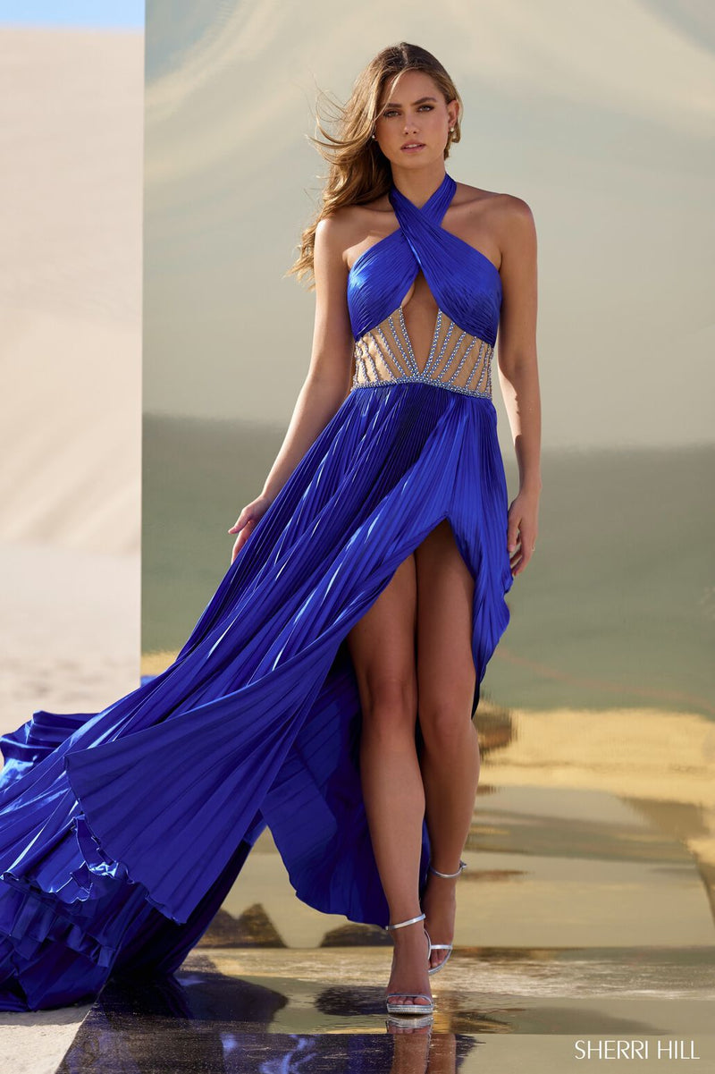 This gown features charmeuse pleated fabric with a criss-cross neckline, an illusion sheer beaded waistband, and a skirt slit. This dress is unique and one of a kind. Shine at your next pageant, prom or event in this stunning gown.  Sherri Hill 56473