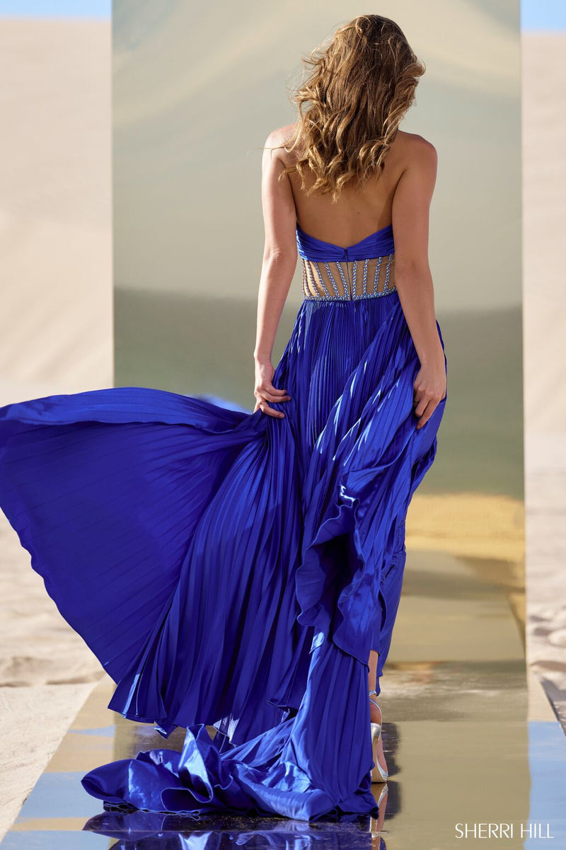 This gown features charmeuse pleated fabric with a criss-cross neckline, an illusion sheer beaded waistband, and a skirt slit. This dress is unique and one of a kind. Shine at your next pageant, prom or event in this stunning gown.  Sherri Hill 56473