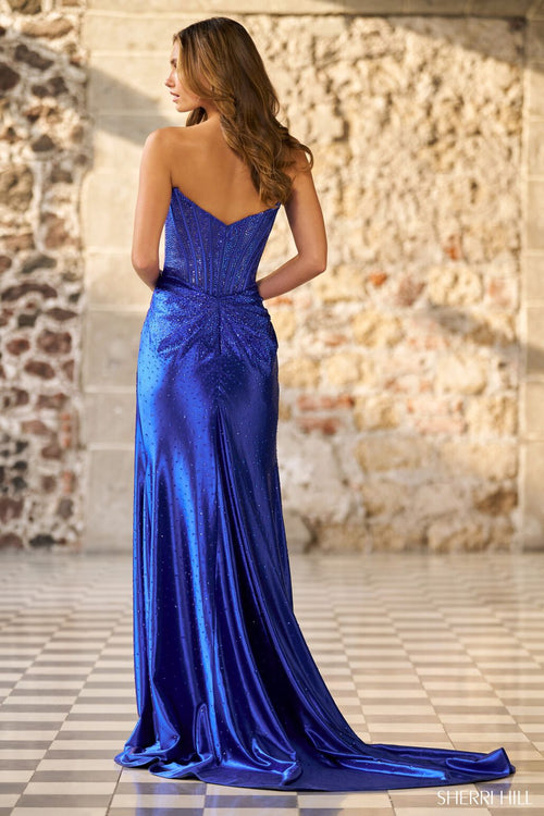 This gown features a strapless neckline with hot fix stones throughout the fabric, a corset bodice, and a high skirt slit. This dress has all the unique details to impress at your next pageant, prom or formal event.  Sherri Hill 56620