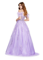 This remarkable ballgown features a cold-shoulder neckline with crystal stone detailed spaghetti straps and a feather off-the-shoulder embellishments. The bodice is partly sheer with corset boning, lace detailing and a crystal stone embellished waistline belt. The feathers and lace continue down through the skirt with an A-line silhouette and tulle fabric. This dress is a magical choice for your next prom or formal event.  Ashley Lauren 11447