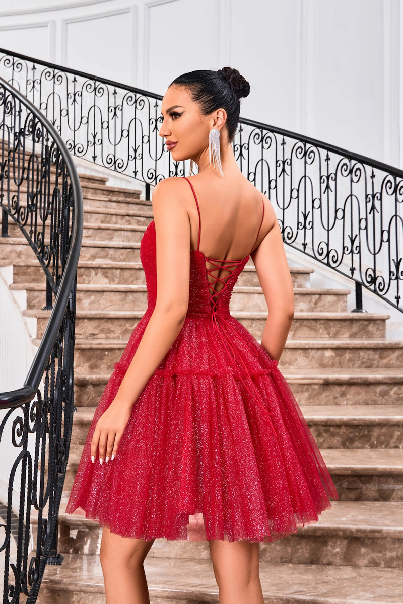 This cocktail dress features a straight across neckline with spaghetti straps and a lace-up back. The glitter tulle fabric creates an A-line silhouette and a playful vibe. Style this dress to make it your own at your next homecoming, sweethearts or formal event.  JAD J24090