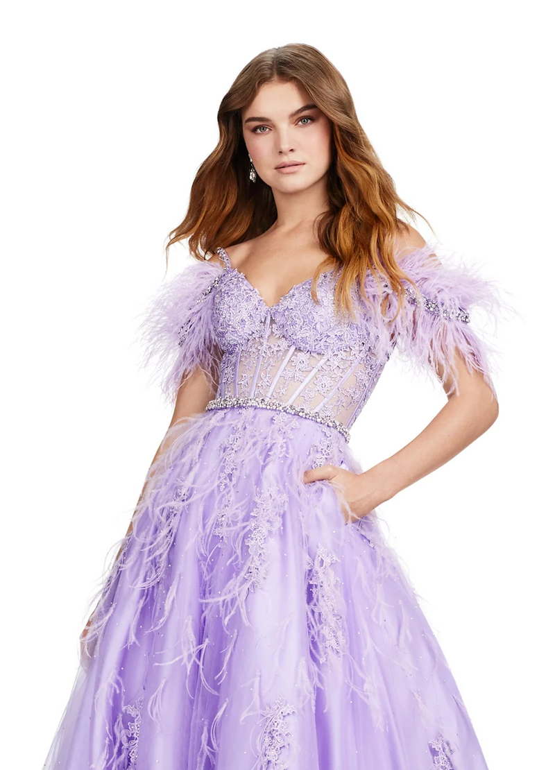 This remarkable ballgown features a cold-shoulder neckline with crystal stone detailed spaghetti straps and a feather off-the-shoulder embellishments. The bodice is partly sheer with corset boning, lace detailing and a crystal stone embellished waistline belt. The feathers and lace continue down through the skirt with an A-line silhouette and tulle fabric. This dress is a magical choice for your next prom or formal event.  Ashley Lauren 11447
