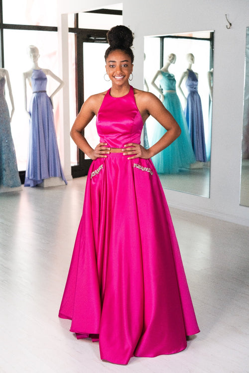 This ABU 6412 two-piece flowy gown in fuchsia features a high neck bodice, beading embellishments on the pockets, and an open back.