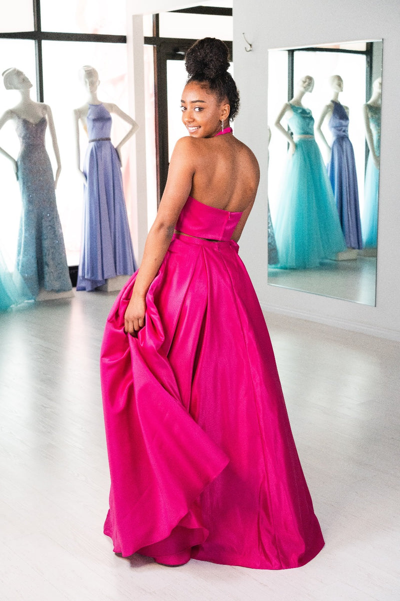 This ABU 6412 two-piece flowy gown in fuchsia features a high neck bodice, beading embellishments on the pockets, and an open back.